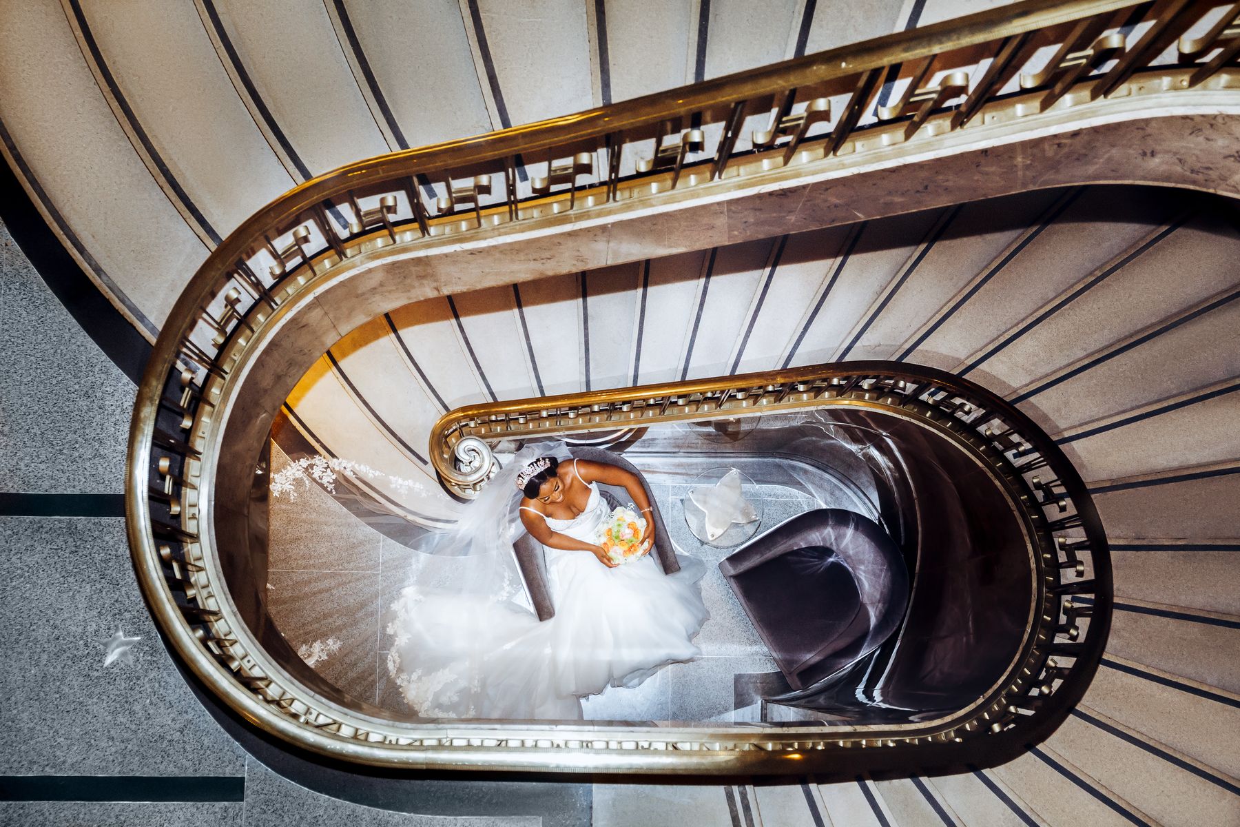 Looking down a gold spiral staircase at the couple